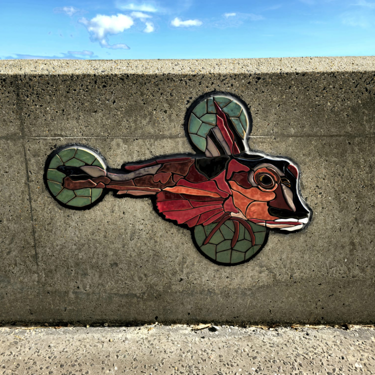 A mosaic rendering of a fish embedded on the coastal wall