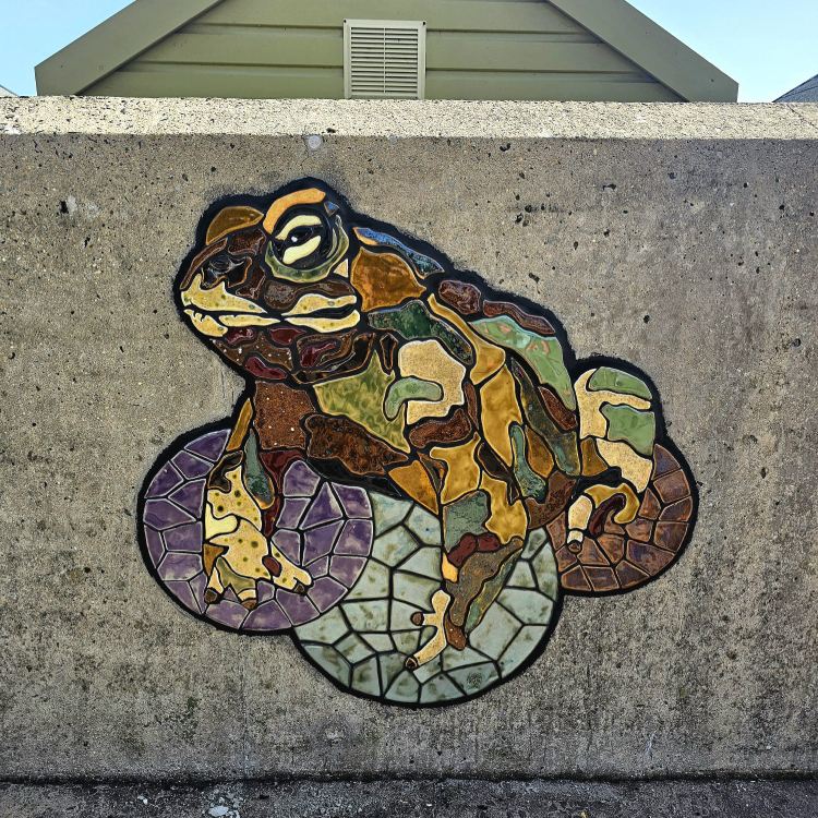 A mosaic rendering of a frog embedded on the coastal wall